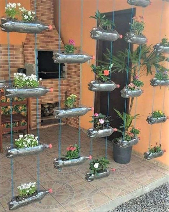 Un exemple inspirant de mini-potager recyclé utilisant des bouteilles en plastique et des palettes en bois pour cultiver des herbes aromatiques et des petites laitues sur un balcon