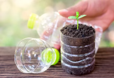 Un exemple inspirant de mini-potager recyclé utilisant des bouteilles en plastique et des palettes en bois pour cultiver des herbes aromatiques et des petites laitues sur un balcon